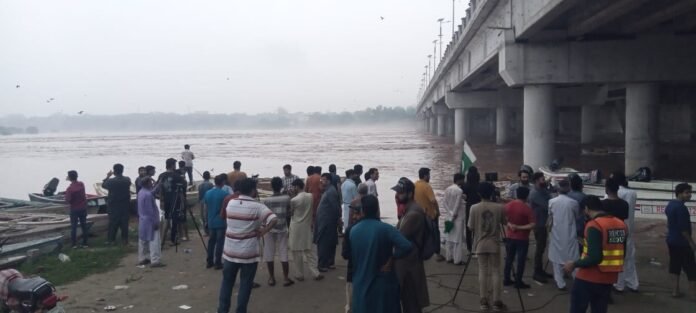 Standing on the eastern bank of River Ravi, people watch the surging floodwaters near bridge connecting Shahdara and Lahore. WE Punjab Photo