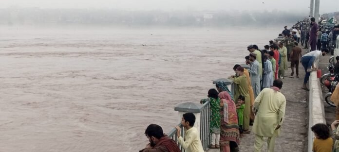 Standing at Shahdara Lahore bridge, people watch surge in waters in River Ravi. WE Punjab photo